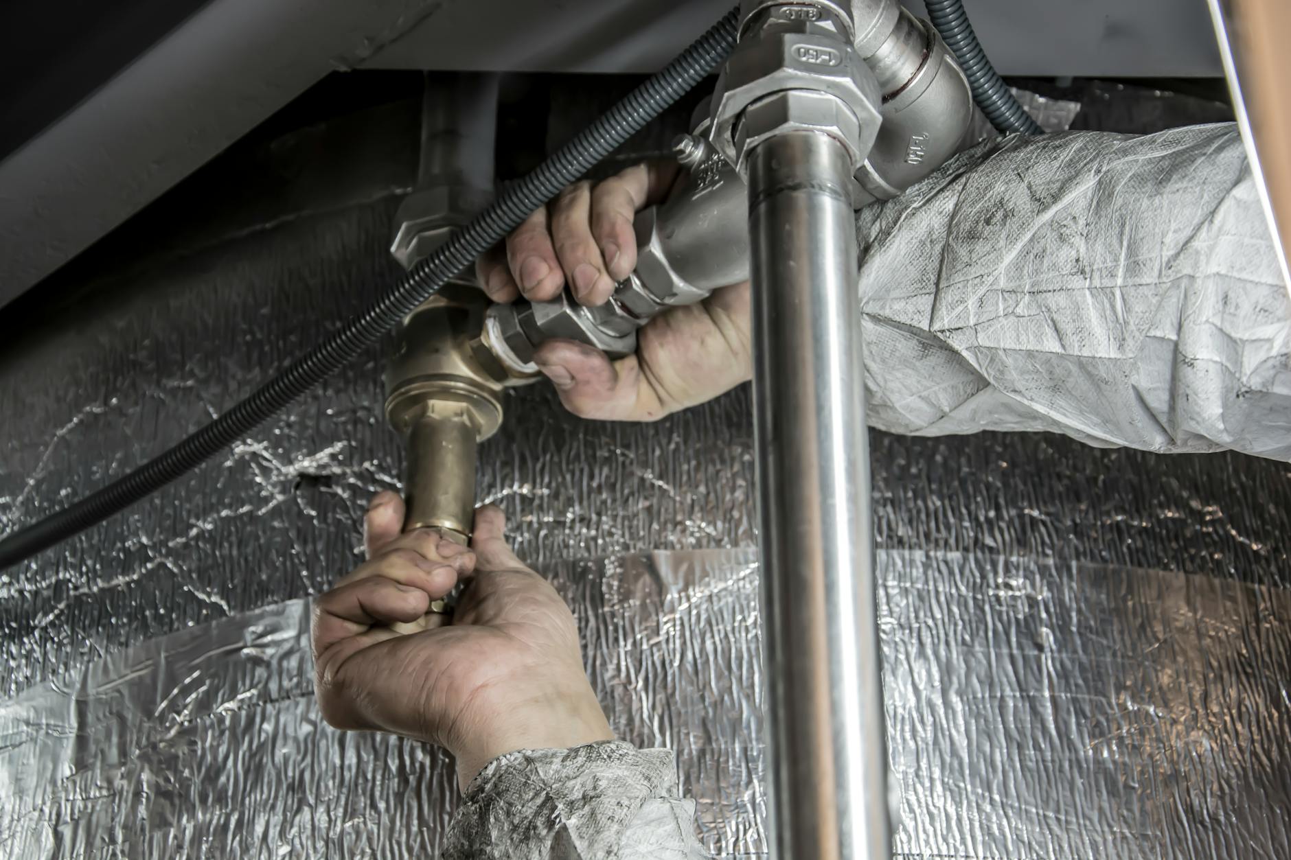 Master plumber's hands gripping a pipe wrench on a copper line
